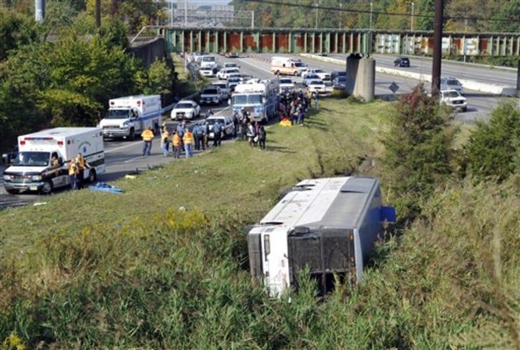 Rescue workers and passengers stand by after a bus overturned in a ditch at an exit ramp off Route 80 in Wayne, N.J., on Saturday.